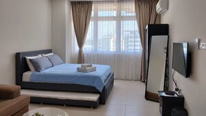 Ein modernes Hotelzimmer mit einem großen Bett, einem Flachbildfernseher, einem Spiegel und einem kleinen Tisch mit einer Pflanze.