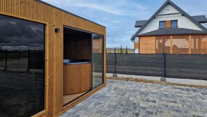 Une structure moderne en bois, dotée d’une grande baie vitrée, d’une terrasse carrelée en pierre et d’un espace clos.