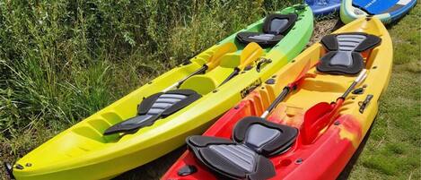 Three kayaks lined up on grass.
