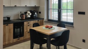 Une cuisine moderne avec des meubles en bois, un plan de travail noir et un coin repas comprenant une table et des chaises.