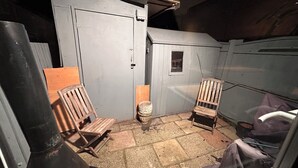 Un petit espace clos comprenant deux chaises en bois, une petite fenêtre et une porte.