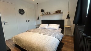 Une chambre à coucher avec un lit, une horloge, une étagère avec des objets décoratifs et une porte.