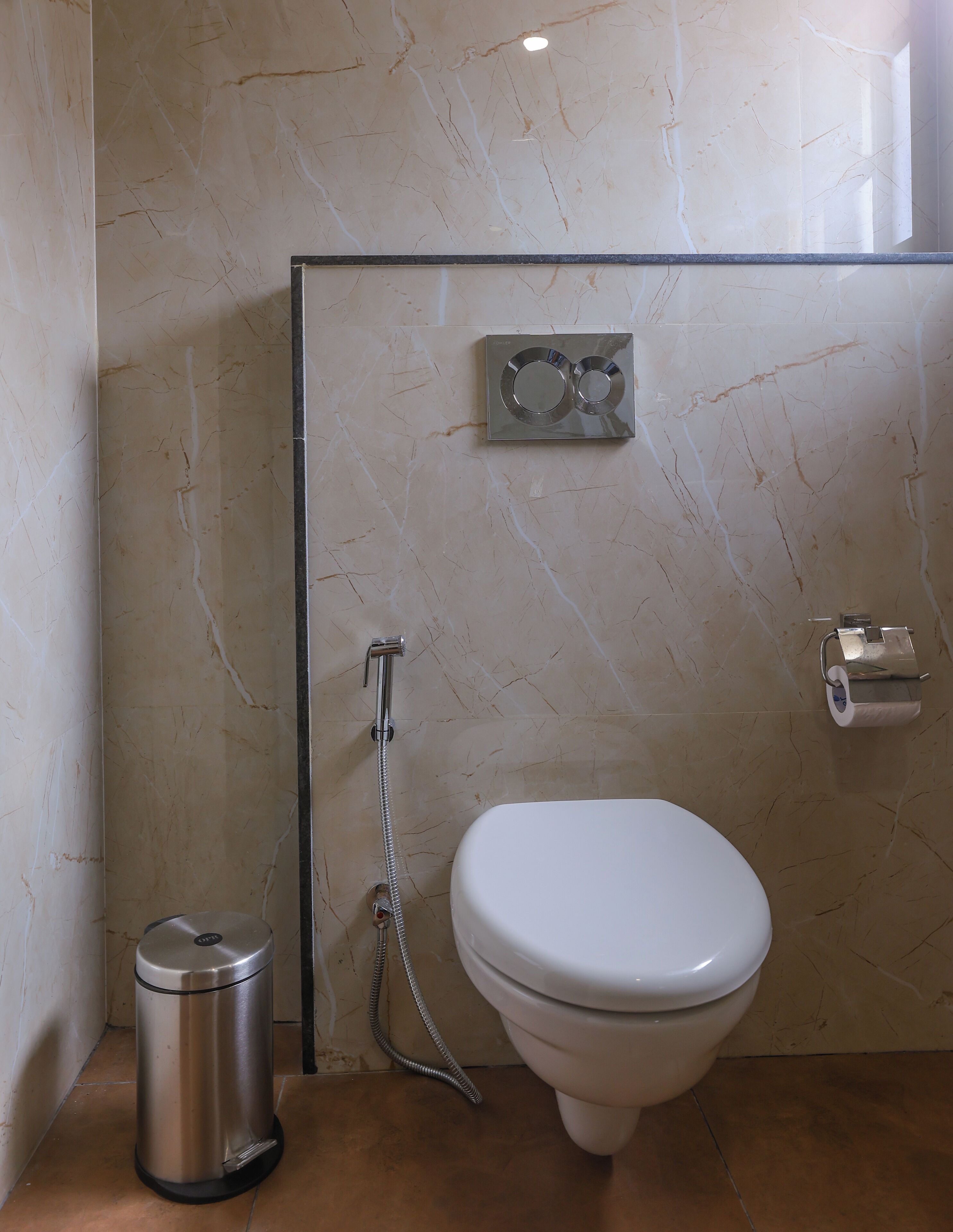 Un baño con inodoro, ducha y cubo de basura.