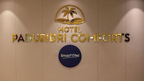 Une enseigne pour l’hôtel Padubidri Comforts, avec un logo représentant un palmier et un logo « Smart Hotel ».