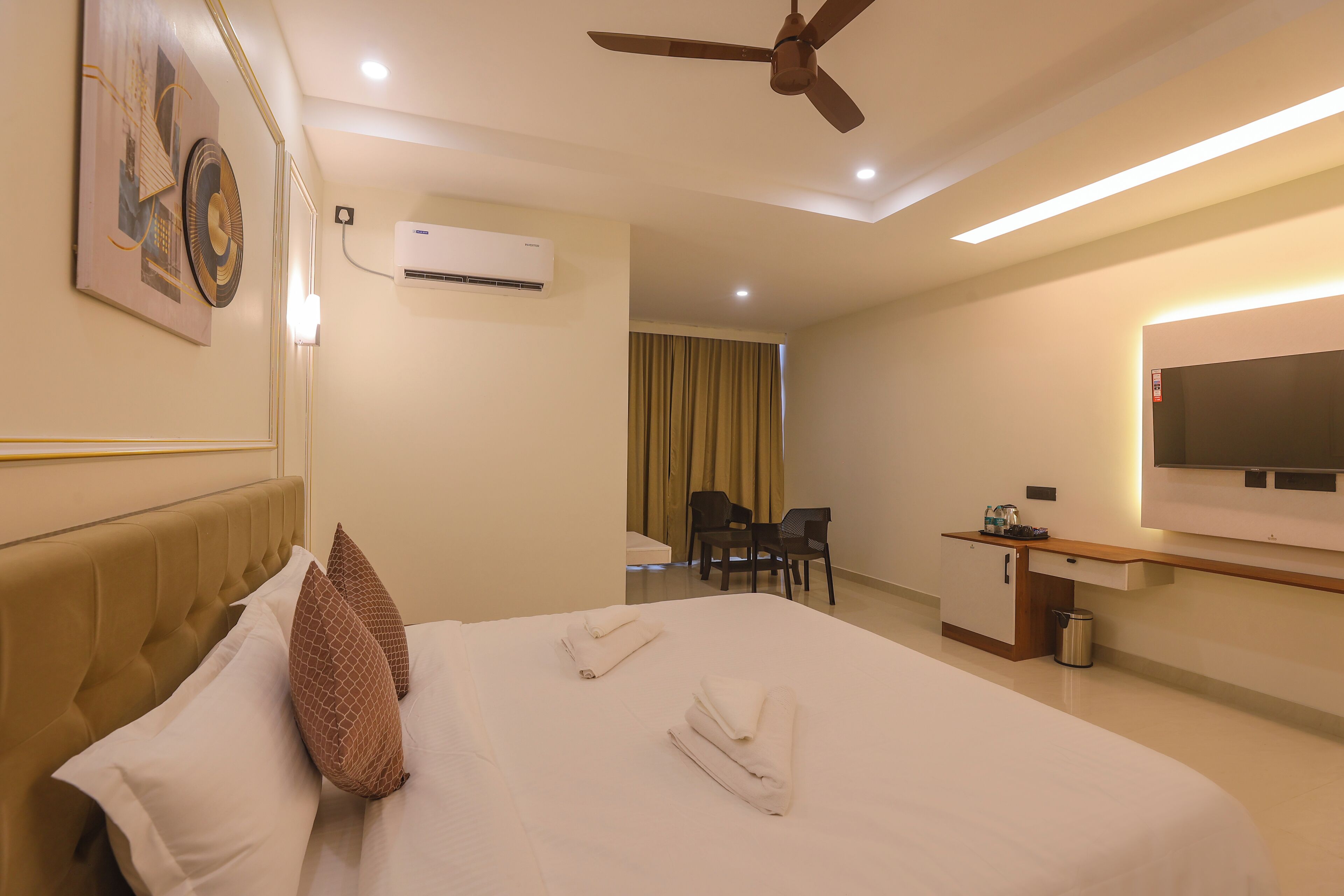 Une chambre d’hôtel équipée d’un lit, d’un ventilateur de plafond, d’un bureau avec une chaise, d’une télévision et d’un appareil de climatisation.