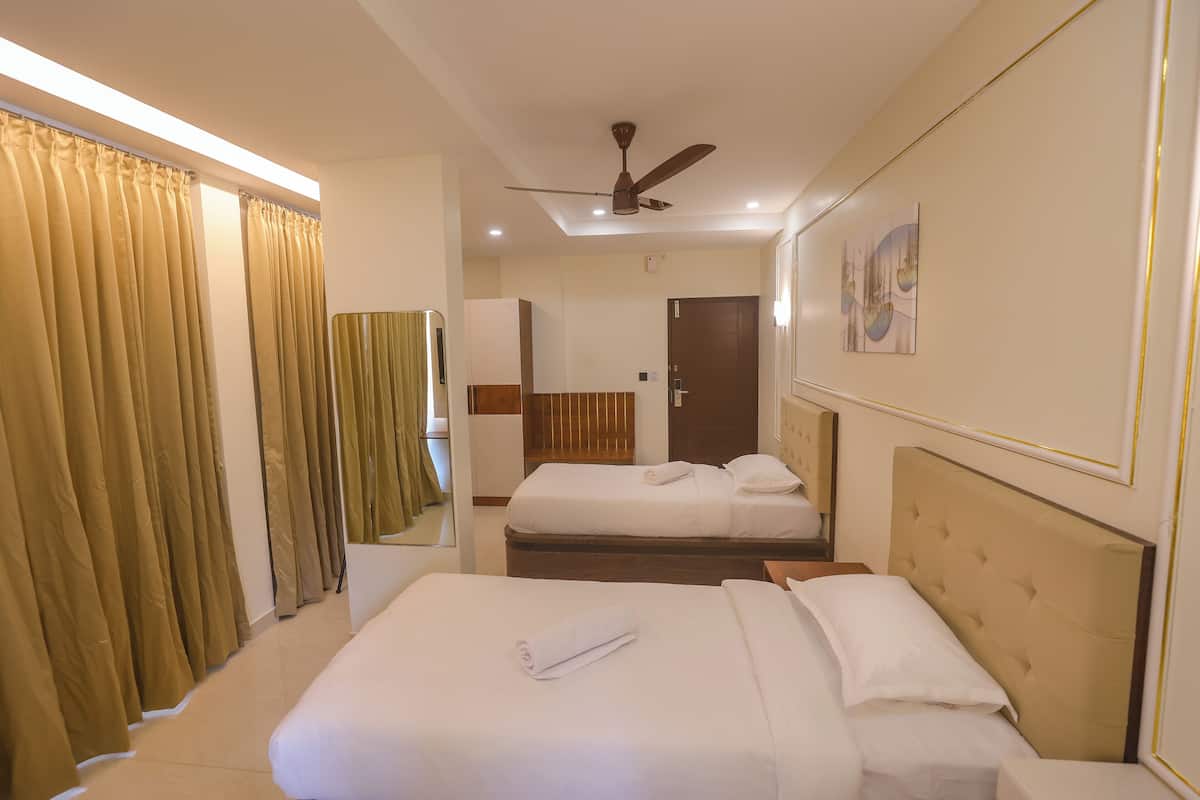 A hotel room with two beds, a ceiling fan, a bathroom with a mirror, and a painting on the wall.