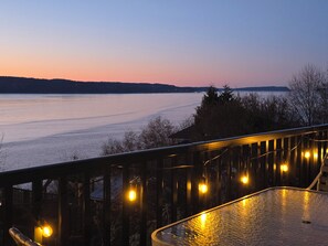 A deck with string lights overlooking a body of water at dusk. - Puget Sound Waterfront Retreat • Ferry & Sunset Views (Mukilteo)