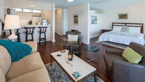 Een moderne hotelkamer met een bed, een slaapbank, een salontafel, een eethoek en een keuken.