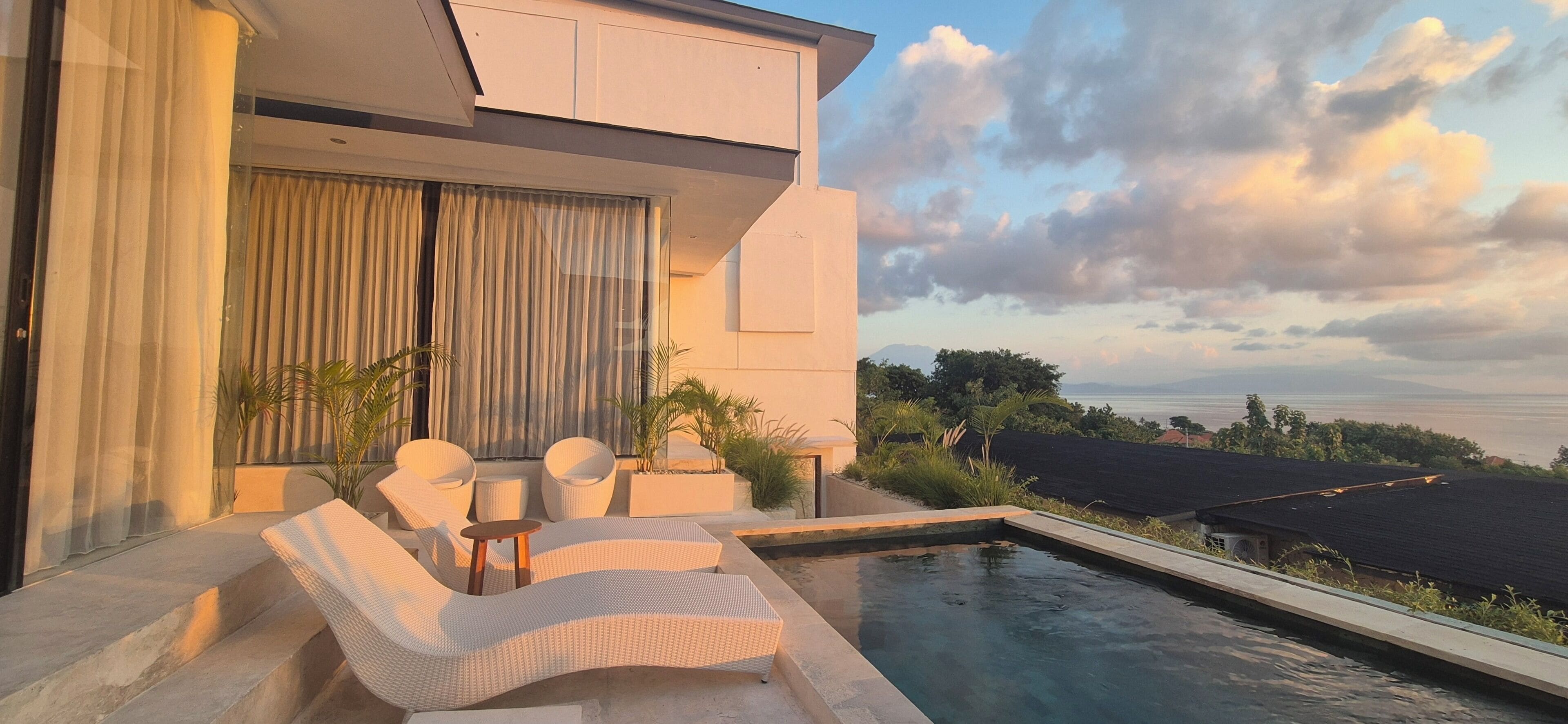 A modern outdoor pool area with lounge chairs and a view of the landscape.