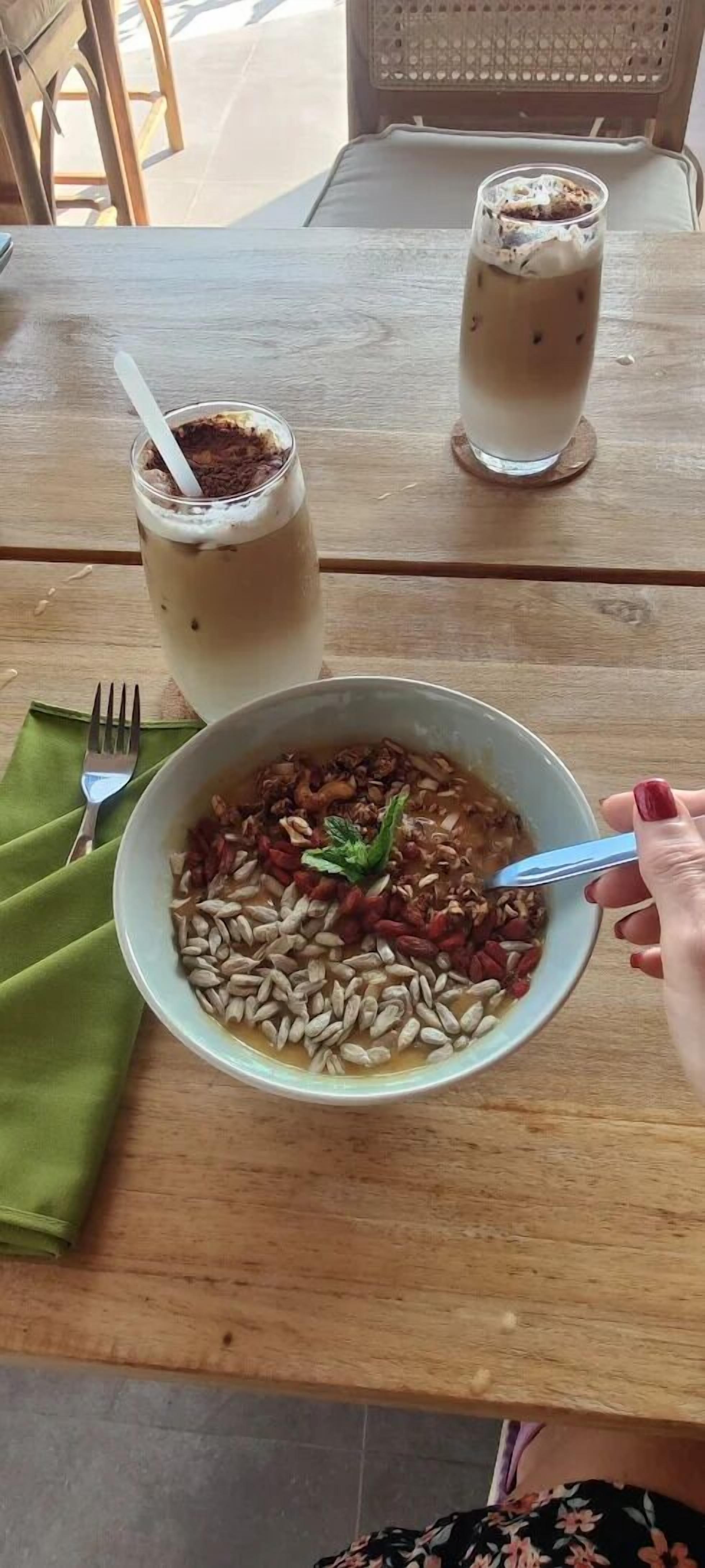 Ein Tisch mit einer Schüssel Essen, zwei Getränken und einer Gabel.