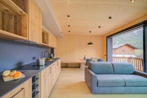 A modern kitchen with wooden cabinets, a black countertop, and a view of a mountain through a large window. - Leba 4, Livigno, Italy (Livigno)