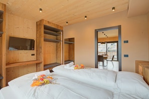 Ein holzgetäfeltes Zimmer im Chalet-Stil mit zwei Betten, einem Fernseher und einer Essecke mit Blick.