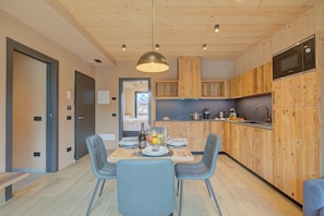 Eine moderne Küche mit Holzausstattung, einer eingebauten Mikrowelle und einem Essbereich mit Tisch für zwei Personen.