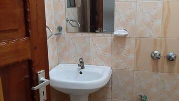 A bathroom with a wooden door, a white sink, a mirror, and patterned tiles.