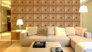 A modern living room with a beige sofa, a coffee table, and a patterned wall.