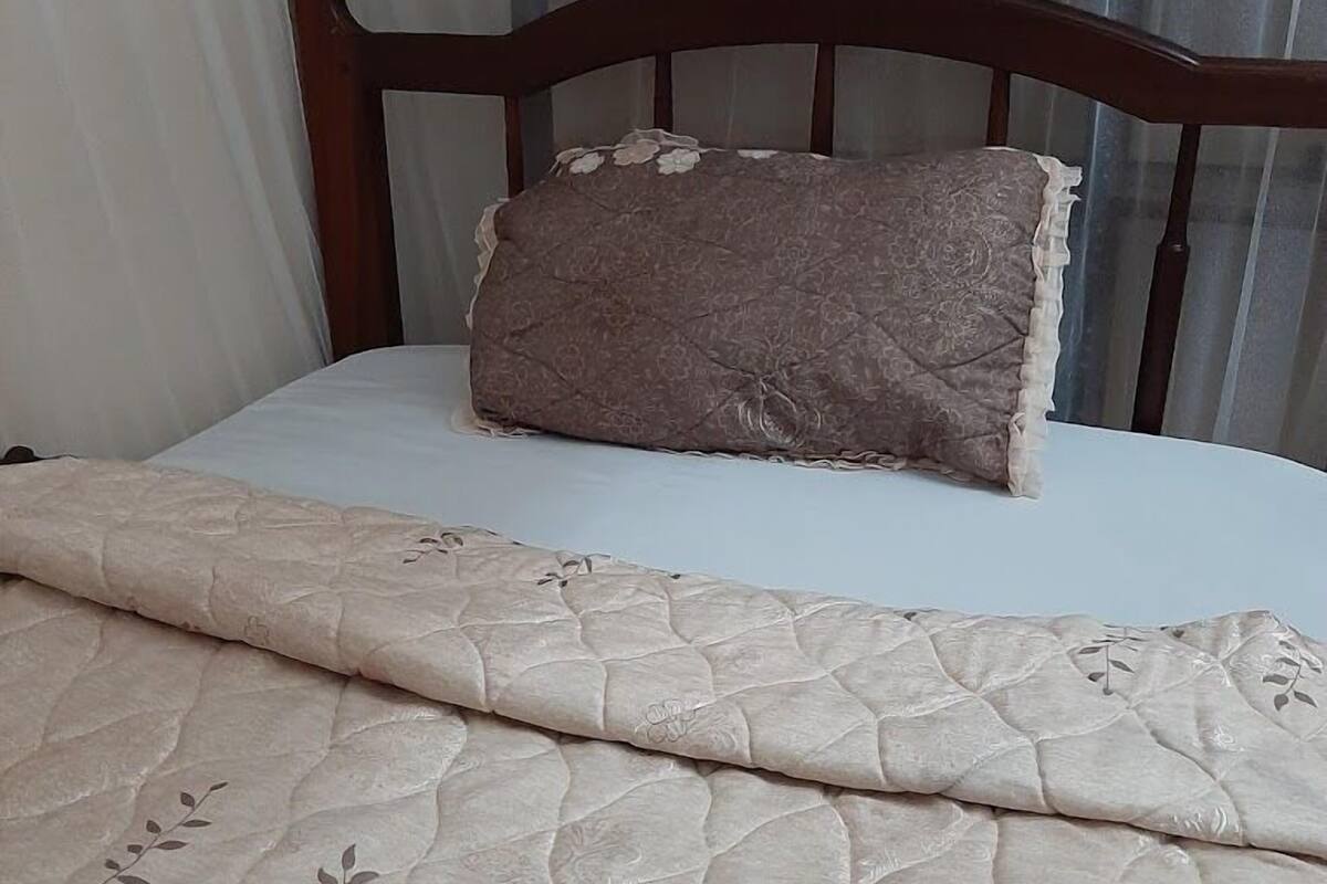 Un lit avec une couvre-lit à motifs floraux et un oreiller marron.