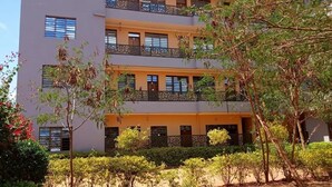 A multi-story building with balconies and a sign reading "MAGHONYI RESORT".