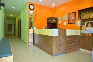 Una zona de recepción con un mostrador de madera, un reloj y carteles religiosos en la pared.