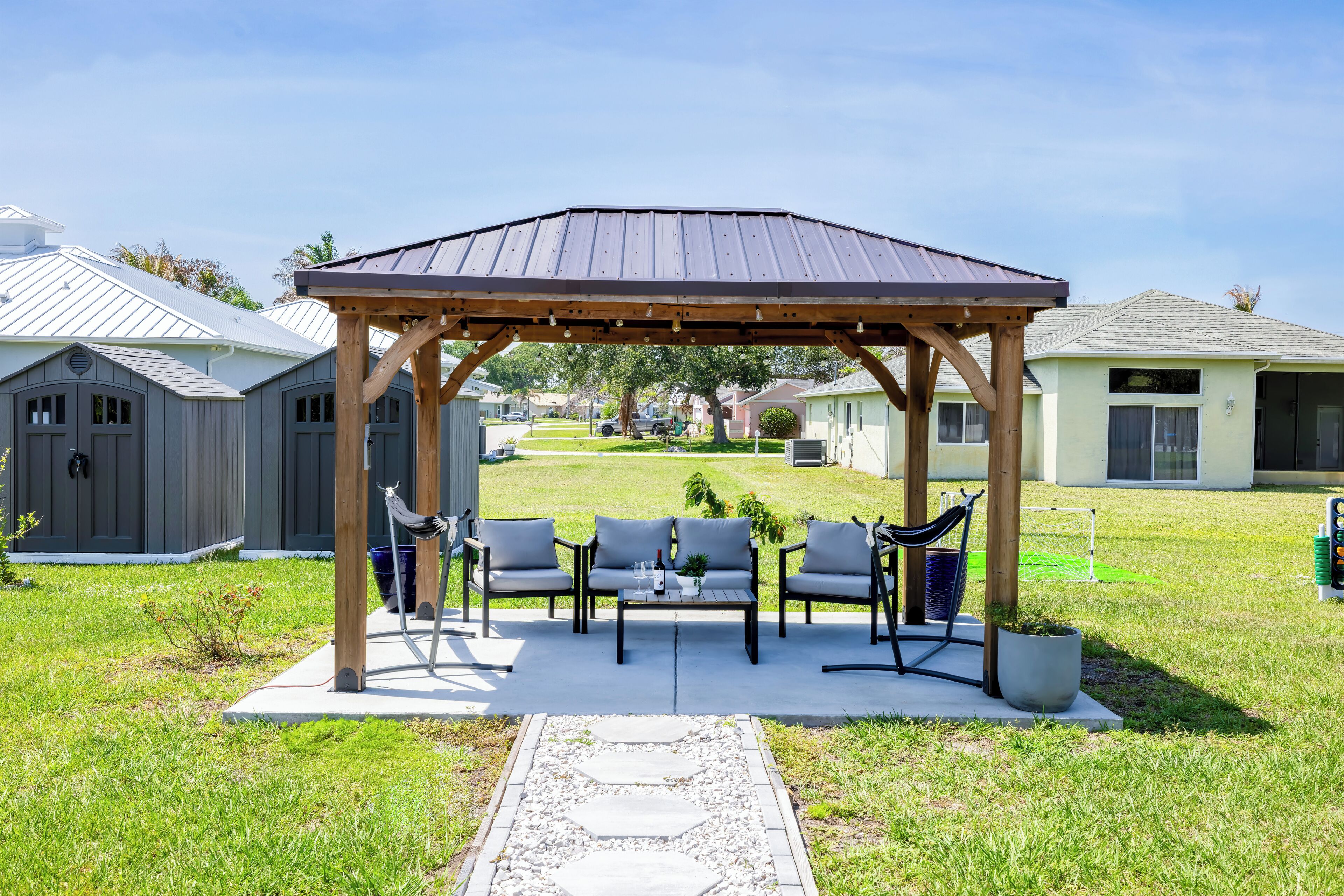 Ein überdachter Außenbereich mit Pergola, Tisch und Stühlen.
