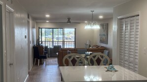 Une cuisine spacieuse dotée d’un îlot central, un coin repas avec une table et des chaises, et un salon avec un canapé et des fauteuils.