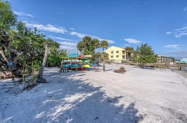 A sandy beach with a building in the background, palm trees, and a clear sky. - Sweet Water Stay - 2 bedroom, 2 bath, condo with fishing dock and heated pool! (Port Charlotte)