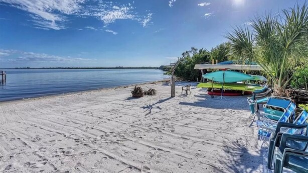 Une plage avec un ciel dégagé, une eau calme et une rangée de chaises et de parasols.