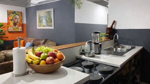 Una cocina compacta con encimera, un lavabo, una estufa y una licuadora.