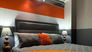 Un dormitorio moderno con una cama grande, dos lámparas de noche y una pared de acento de color llamativo.