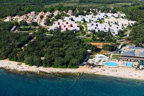 An aerial view of a coastal resort with multiple buildings, a beach, and a pool area. - Holiday Apartment with Terrace (Rovinj)