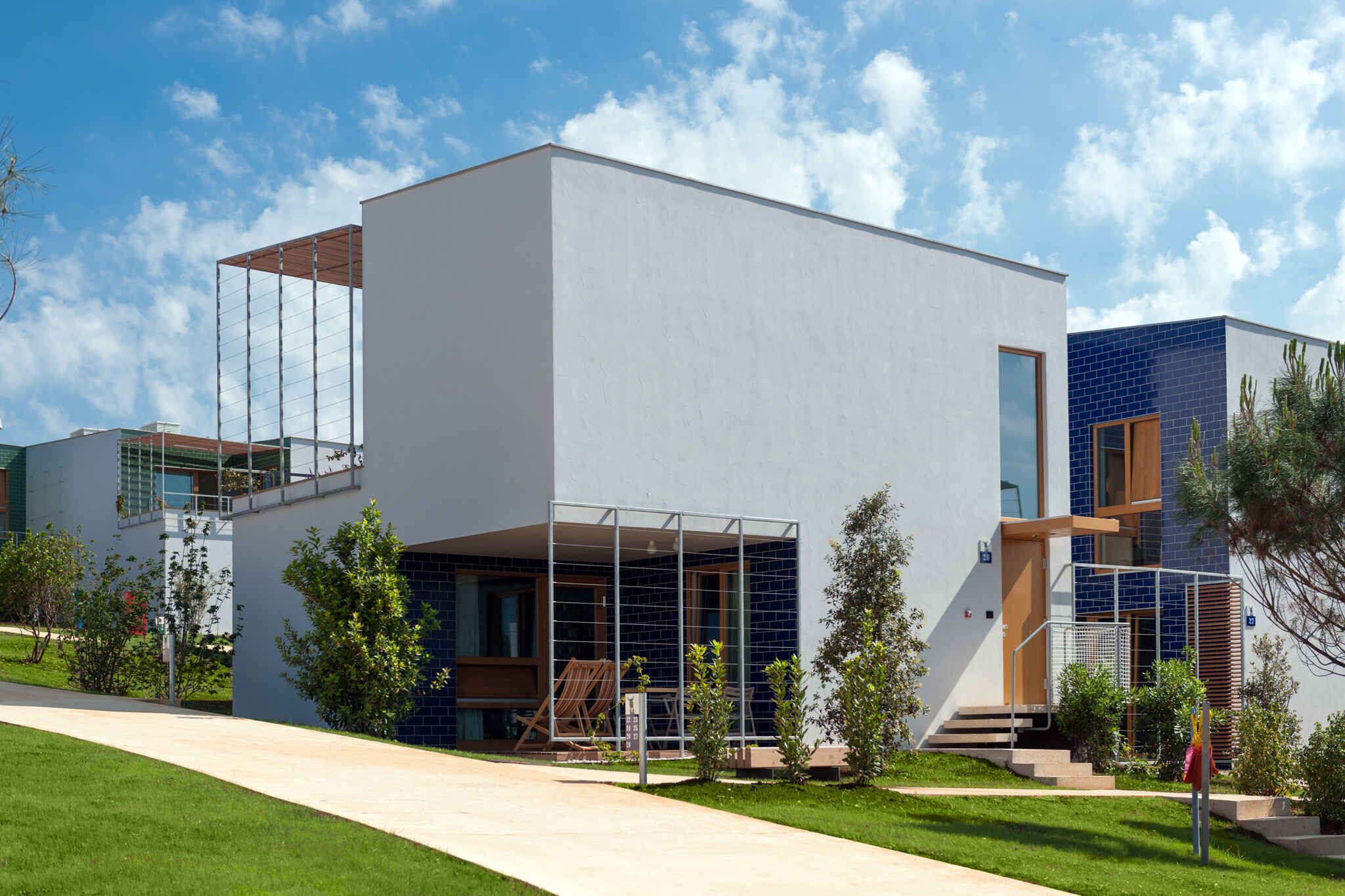 A modern building with a flat roof, large windows, and a covered outdoor area.