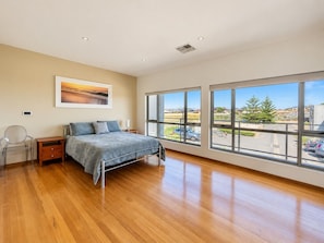 A bedroom with a large bed, a nightstand, a chair, and a window with a view of the outside.