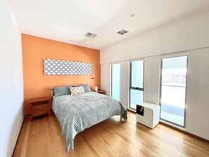 Une chambre à coucher avec un lit, une table de chevet, une commode, une fenêtre et une vue sur l’extérieur.