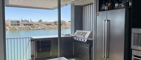 A balcony with a grill, a refrigerator, and a sink.