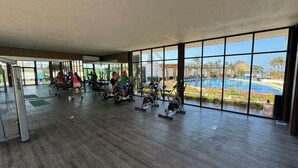 Ein Fitnessraum mit Cardiogeräten und Blick auf Pool und Garten.