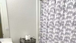 A bathroom with a toilet, a sink, a mirror, a shower curtain with an elephant pattern, and a small rug on the floor. - 5 Min to Caltrain . Shared Bath with 1 Other Guest . Tech (Sunnyvale)