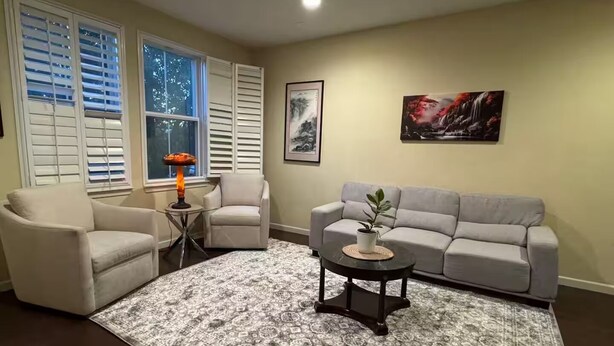 A living room with a patterned rug, a sofa, two armchairs, a small table with a lamp, and a potted plant. - 5 Min to Caltrain . Shared Bath with 1 Other Guest . Tech (Sunnyvale)