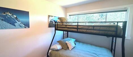 A bunk bed room with a window, a painting on the wall, and a ceiling light fixture.