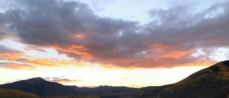 Un valle con una montaña al fondo y un cielo al atardecer.