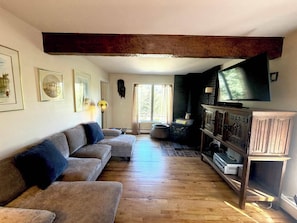 Ein Wohnzimmer mit Sofa, Kamin, Fernseher und Fenster.