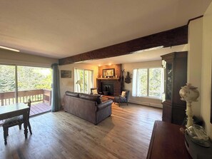 Ein geräumiges Wohnzimmer mit Kamin, Holzboden und einem Balkon.