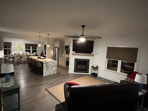 A modern living room with a fireplace, a dining area, and a kitchen with a bar. - Lake Anna: Hot Tub, Pool, Beach, Tennis (Mineral)