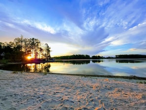 A tranquil lakeside scene with a sandy beach, trees, and a sunset. - New Lake Anna | Hot Tub, Pool, Beach, Fire Pit (Mineral)