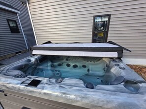Un jacuzzi con tapa, panel de control y un teléfono inteligente a un lado.