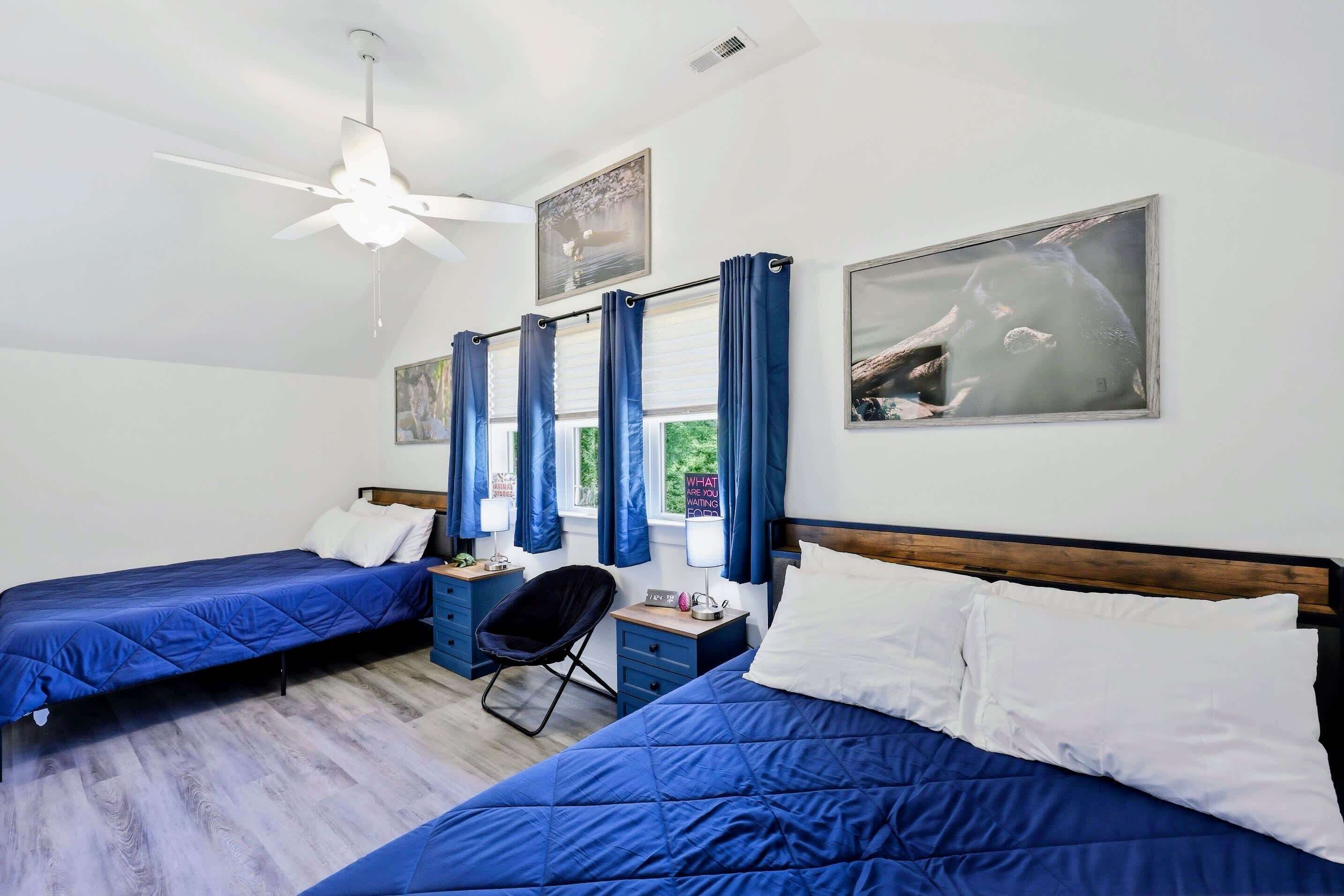 Ein Schlafzimmer mit zwei Betten, einem Deckenventilator, einem Schreibtisch, einem Stuhl und Bildern an den Wänden.