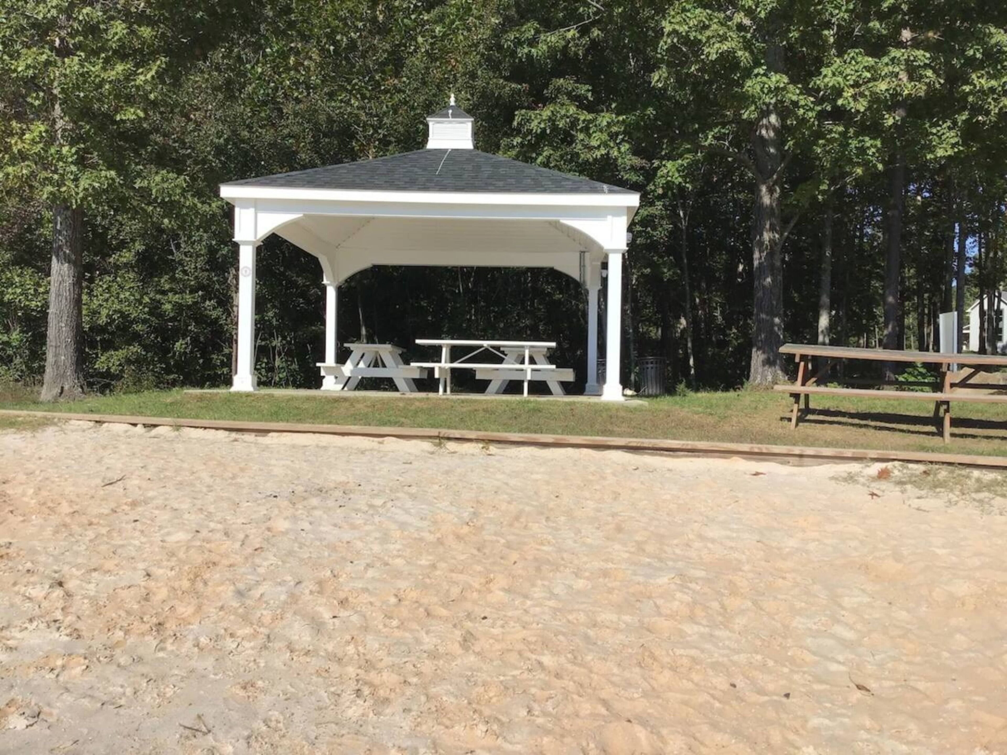 A covered pavilion with picnic tables, surrounded by trees.