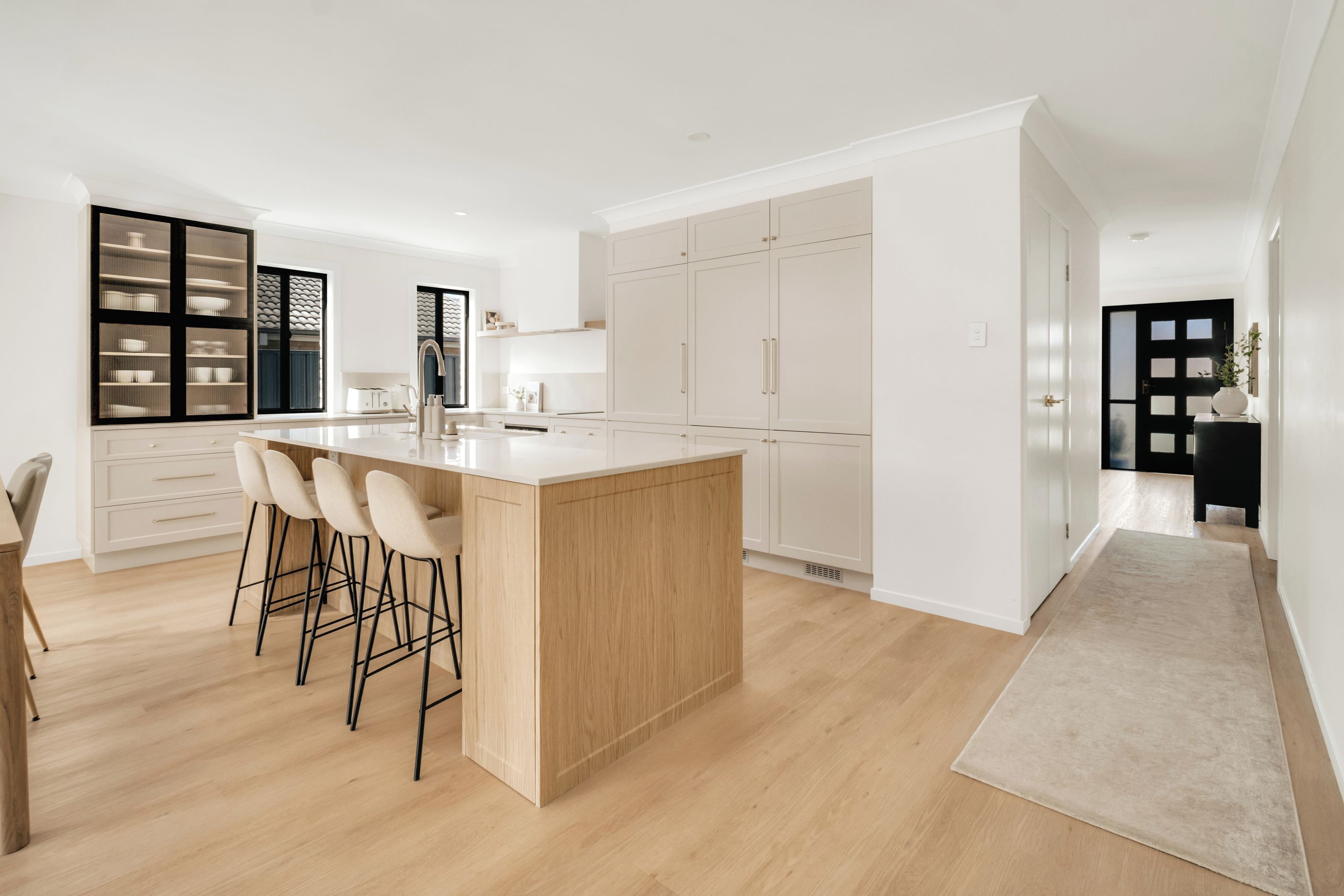 A modern kitchen with a central island, bar stools, and a built-in oven.
