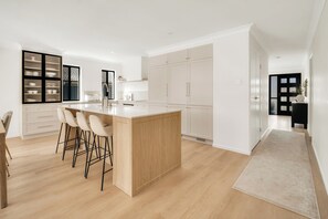 A modern kitchen with a central island, bar stools, and a built-in oven. - Summers Green View Retreat - Kayaks Included (Logan Reserve)