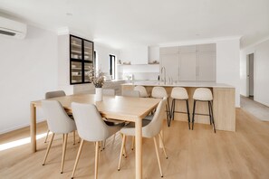 Una cucina moderna con isola centrale, mobili bianchi e zona pranzo con tavolo e sedie in legno.