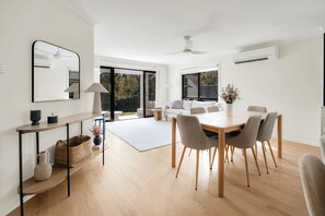 Un soggiorno moderno con zona pranzo, ampie finestre e una ventola a soffitto.