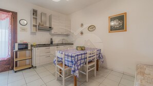 A compact kitchen with white cabinets, a microwave, and a small dining table with checkered tablecloths.